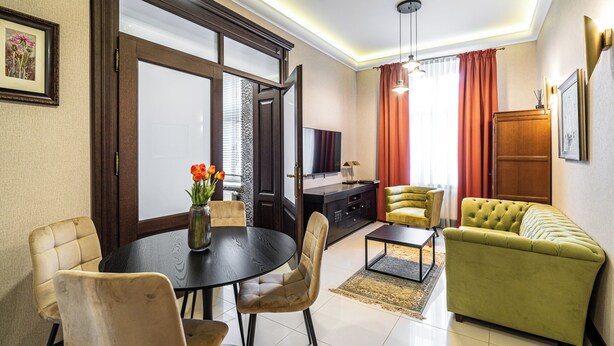 A modern living room with a dining area, a sofa, a TV, and a wooden cabinet. - RentPlanet - Apartamenty Stawowa (Katowice)