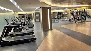 Un gimnasio con cintas de correr, bicicletas estáticas y máquinas de pesas.