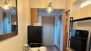 Una sala de estar moderna con una televisión de pantalla plana, una mesa de comedor con vajilla, un espejo y una lámpara en el techo.