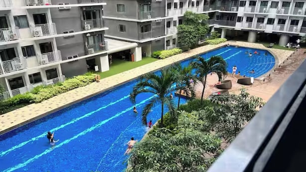 Una piscina rodeada de vegetación y edificios de varios pisos.