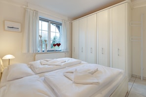 Ein Schlafzimmer mit einem großen Bett, weißen Vorhängen, einem Fenster mit Blick und einem Kleiderschrank.