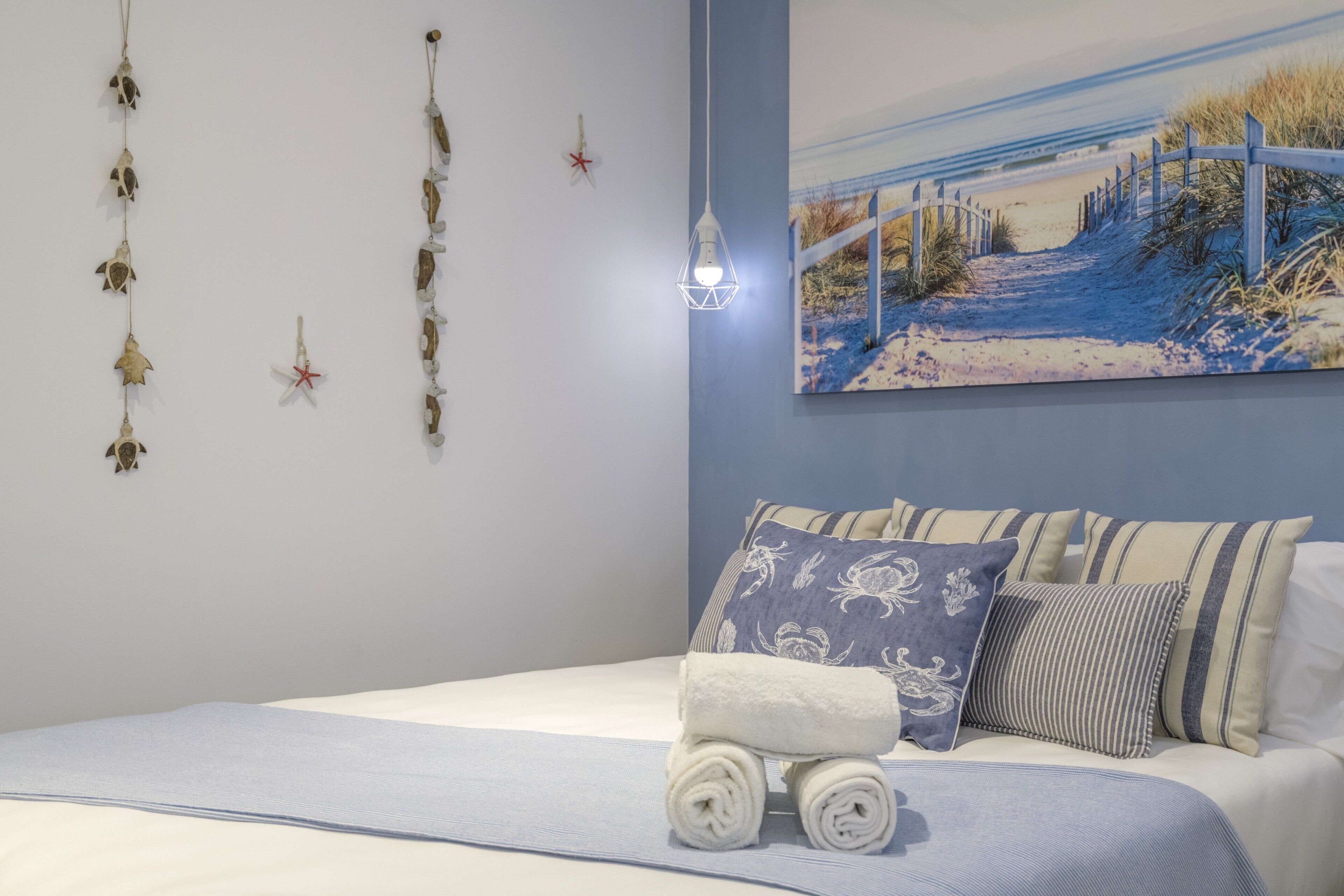 Un dormitorio con cama, almohadas, un tapiz y un cuadro.