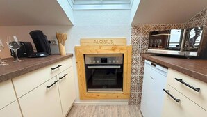 A compact kitchen with a skylight, a Bosch dishwasher, and a wooden sign above the oven. - Aloisius | Balcony Apt · Workation · Königscard (Nesselwang)