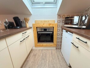 Una cocina compacta con tragaluz, lavavajillas Bosch y un letrero de madera sobre el horno.