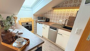 A compact kitchen with a skylight, a microwave, a dishwasher, and a wooden countertop. - Aloisius | Balcony Apt · Workation · Königscard (Nesselwang)