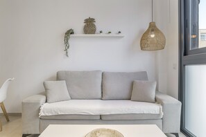 A modern living room with a grey sofa, a white coffee table, a hanging wicker light, and a white shelf with decorative items. - Comfortable "Black Palm" Studio, Excellent Location – Perfect for Couples (Tarifa)