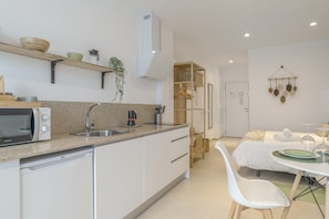 A modern kitchen with a microwave, sink, and wooden shelves. - Comfortable "Black Palm" Studio, Excellent Location – Perfect for Couples (Tarifa)