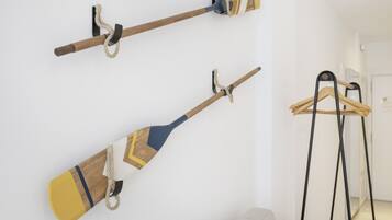 Two wall-mounted paddles, a light-colored sofa, and a black hanger stand in a room.