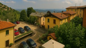A residential area with yellow buildings, a parking lot with cars, and a view of the sea in the background. - Monti Como Lake apartament (Brunate)