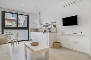 A modern kitchen with white cabinets, a microwave, and a flat-screen TV on the wall.