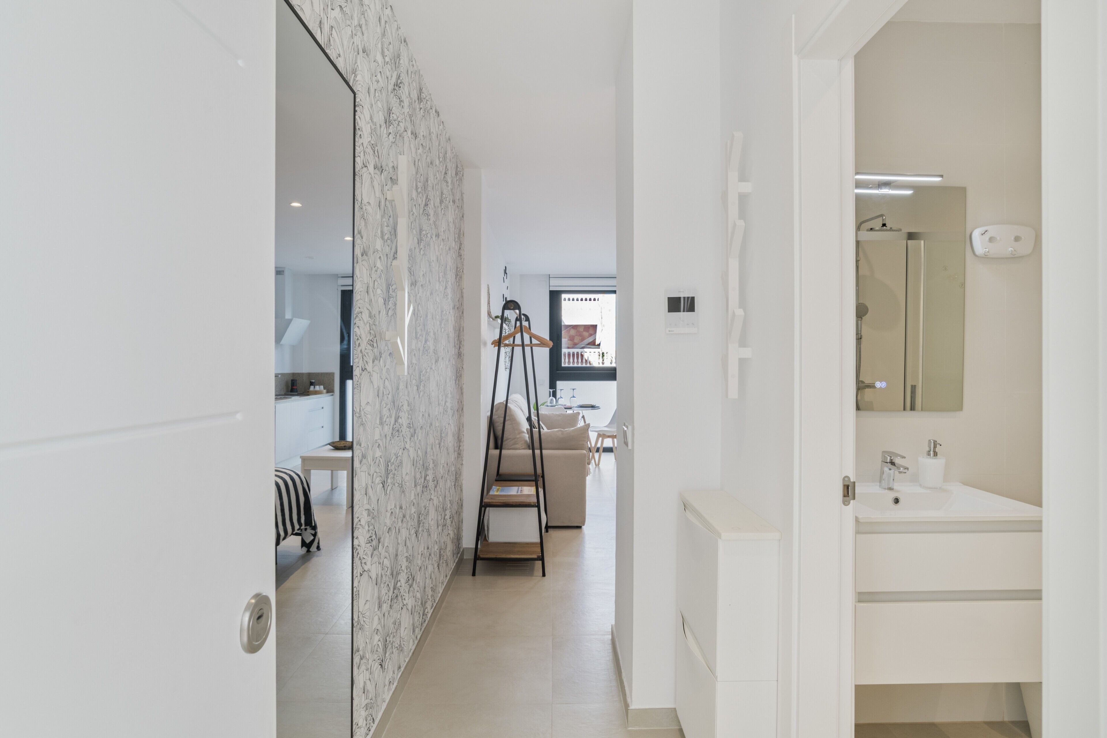 Een moderne badkamer met een wit wastafel, spiegel en handdoekhouder.