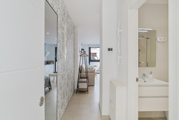 Une salle de bain moderne avec un lavabo blanc, un miroir et un porte-serviettes.