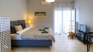 Un dormitorio con cama, televisión, escritorio y silla.