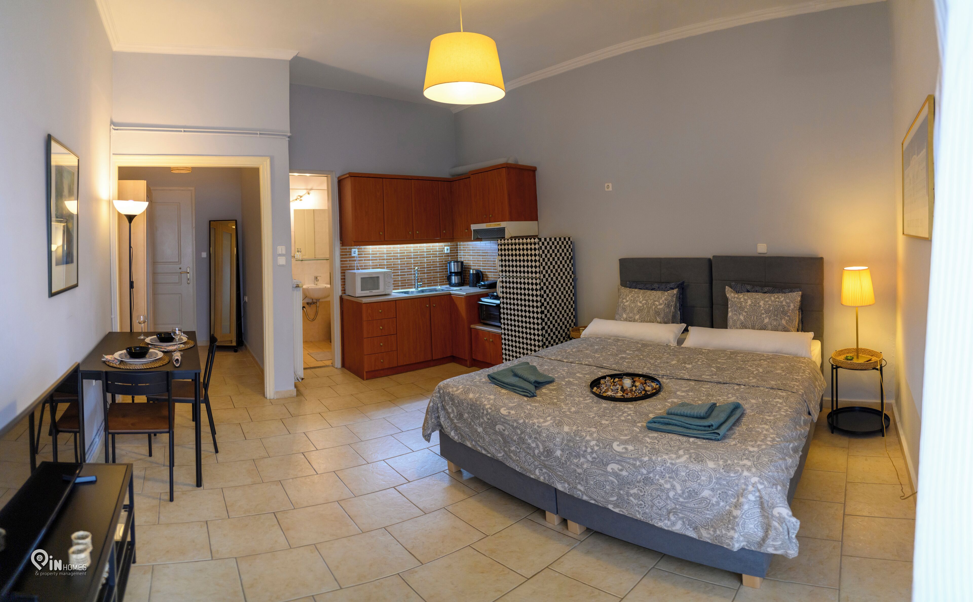 Un dormitorio pequeño con cama, mesita de noche y una kitchenette.
