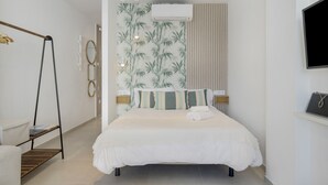 Een slaapkamer met een bed, een hangstoel, een wandairconditioner en een televisie.