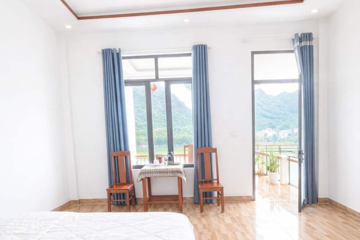 Une chambre d’hôtel avec un grand lit, une table à manger avec des chaises et une vue sur les montagnes par les fenêtres.