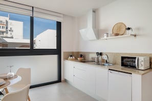 A modern kitchen with white cabinets, a microwave, a sink, and a window overlooking buildings. - Comfortable Studio "The Stairs" – Excellent Location, Perfect for Couples (Tarifa)