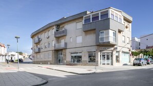 A multi-story building with balconies, a ground-level shop, and a visible sign for 'JUAN SERPA.' - 'San Mateo Loft' Studio with Communal Pool, Wi-Fi, and Air Conditioning (Tarifa)