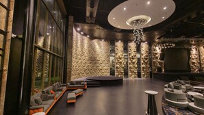 Uma área de estar ampla, com palco, assentos confortáveis e uma parede com textura única.