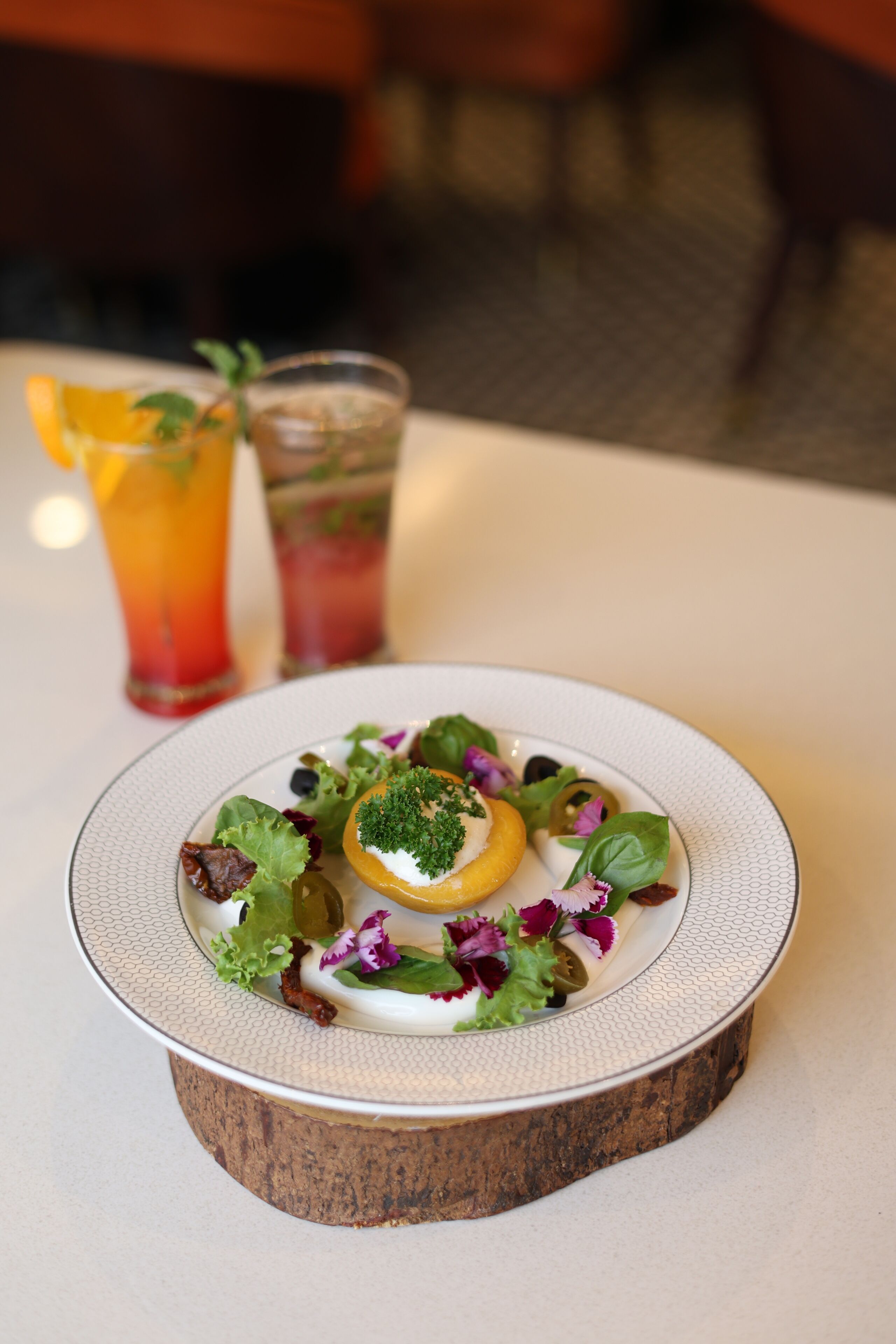 Une assiette de nourriture agrémentée d’un élément décoratif au centre, accompagnée de deux boissons sur la table.