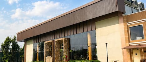 A modern building with a swimming pool, large windows, and a well-maintained garden.