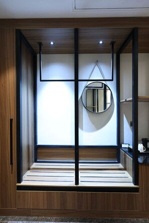 Een moderne kamer met een houten vloer, een ronde spiegel en een zithoek.
