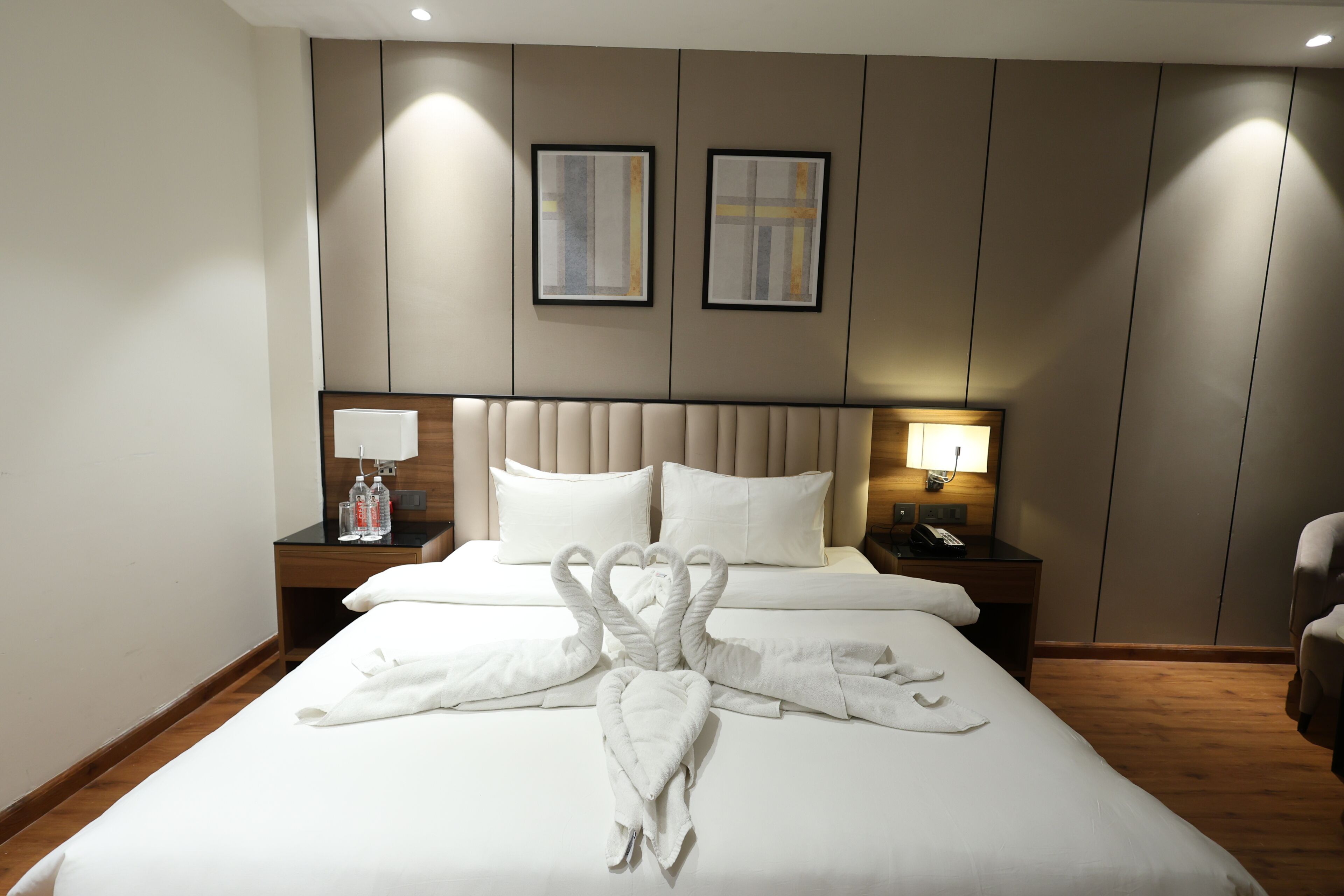 Habitación de hotel con una cama, dos almohadas, cabecero, mesita de noche con lámpara y una silla.