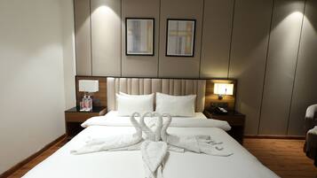 Habitación de hotel con una cama, dos almohadas, cabecero, mesita de noche con lámpara y una silla.
