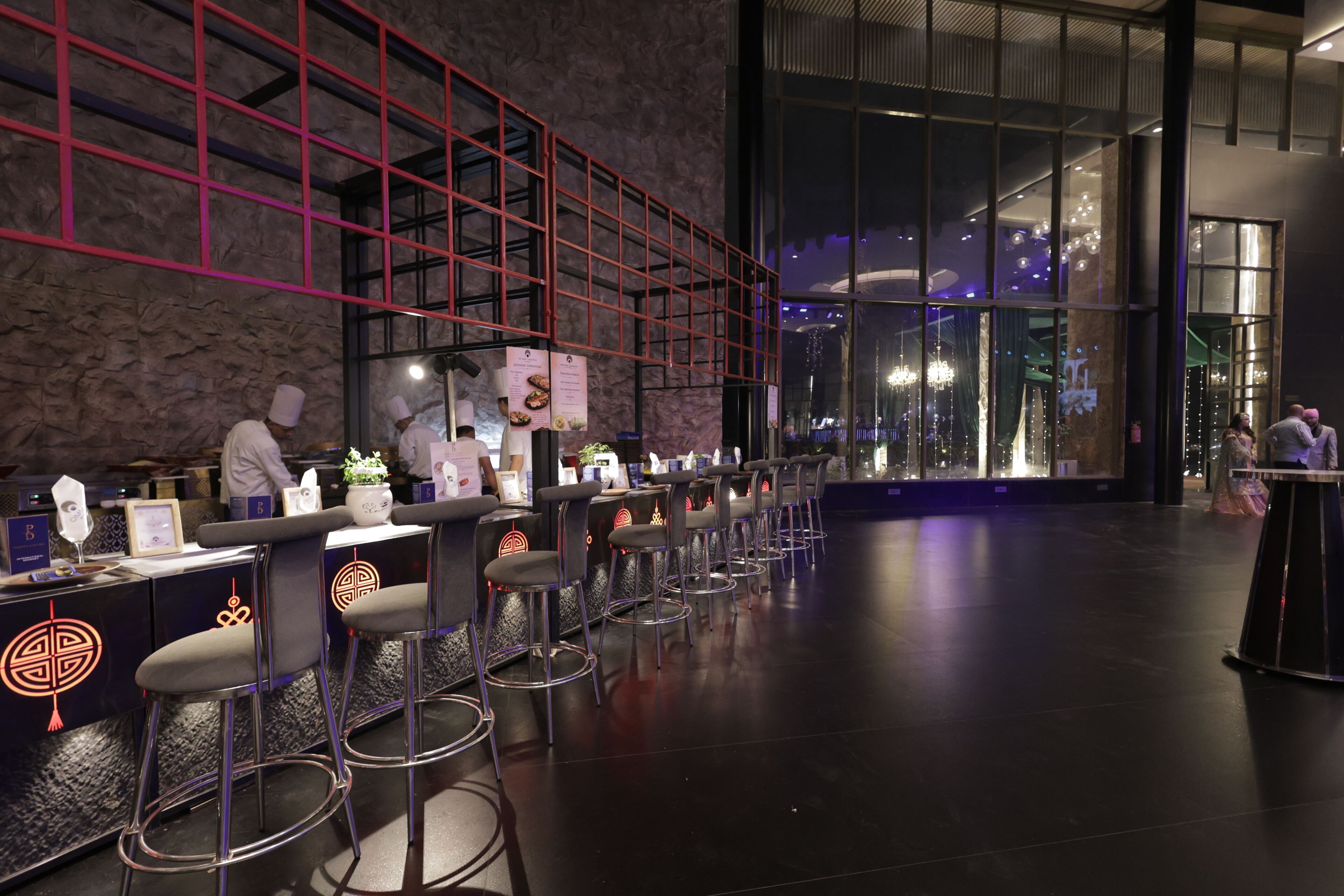 A modern bar area with high stools, a stone wall, and a red grid structure.