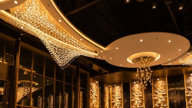 Um hall luxuoso com teto curvo, amplo espaço de estar e um lustre decorativo.