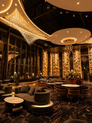 Un lobby lujoso con techo curvo, amplia zona de estar y un candelabro decorativo.