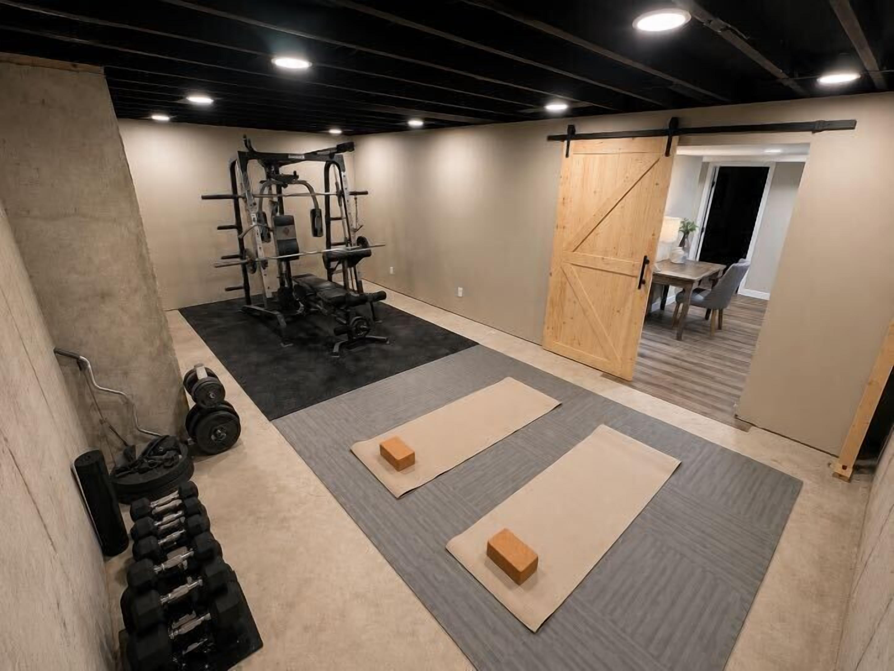 Una palestra con attrezzatura per l'allenamento con i pesi, tappetini e una porta scorrevole.