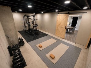 A gym with weightlifting equipment, mats, and a sliding door. - 5BR Pool Oasis | Firepit & Group Retreat (Wentzville)