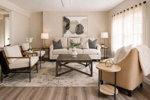 A living room with a sofa, armchairs, a coffee table, and two side tables with lamps.