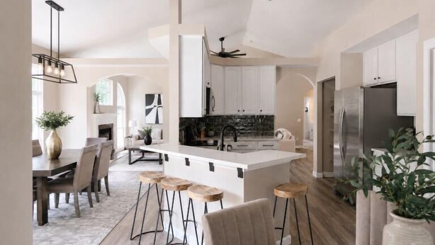 A modern kitchen with a central island, bar stools, and a dining area with a fireplace. - 5BR Pool Oasis | Firepit & Group Retreat (Wentzville)