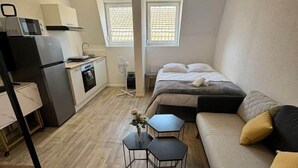 A compact living space with a kitchenette, a bed, and a small dining area. - Les roses" studio: cosy and comfortable (Mulhouse)
