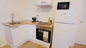 Une cuisine de taille réduite équipée d’un évier, d’une cuisinière, d’un four, d’un four à micro-ondes et d’un réfrigérateur.