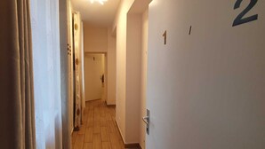 A narrow hallway with a wooden floor, white walls, and doors numbered 1 and 2. - Group Stay 3 Apts Near Enkplatz (Vienna)