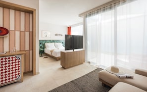 Una habitación de hotel moderna con cama, televisor, escritorio y sofá.