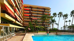 Ein Hotel mit Swimmingpool, Palmen und blauem Himmel.