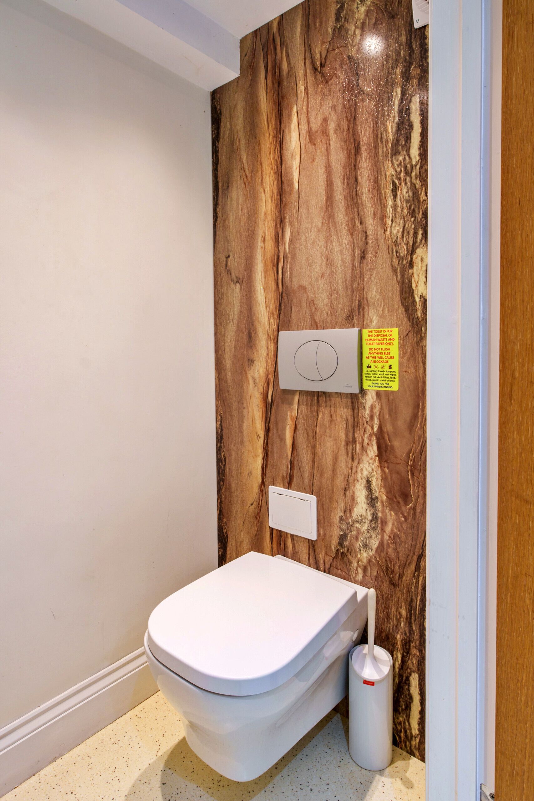 Un baño moderno con pared de mármol, inodoro, bidé y secamanos.