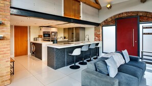 Een moderne keuken met een centraal eiland, barkrukken en een rode deur.