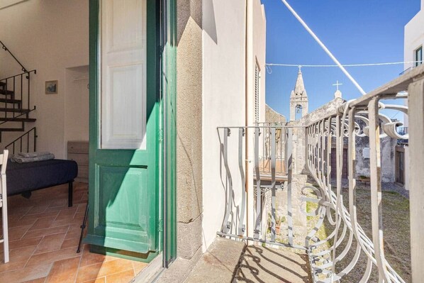 A balcony with a view of a church steeple, a door, and a staircase. - Pietra Longa - Apartment with sea-view terrace (Lipari)