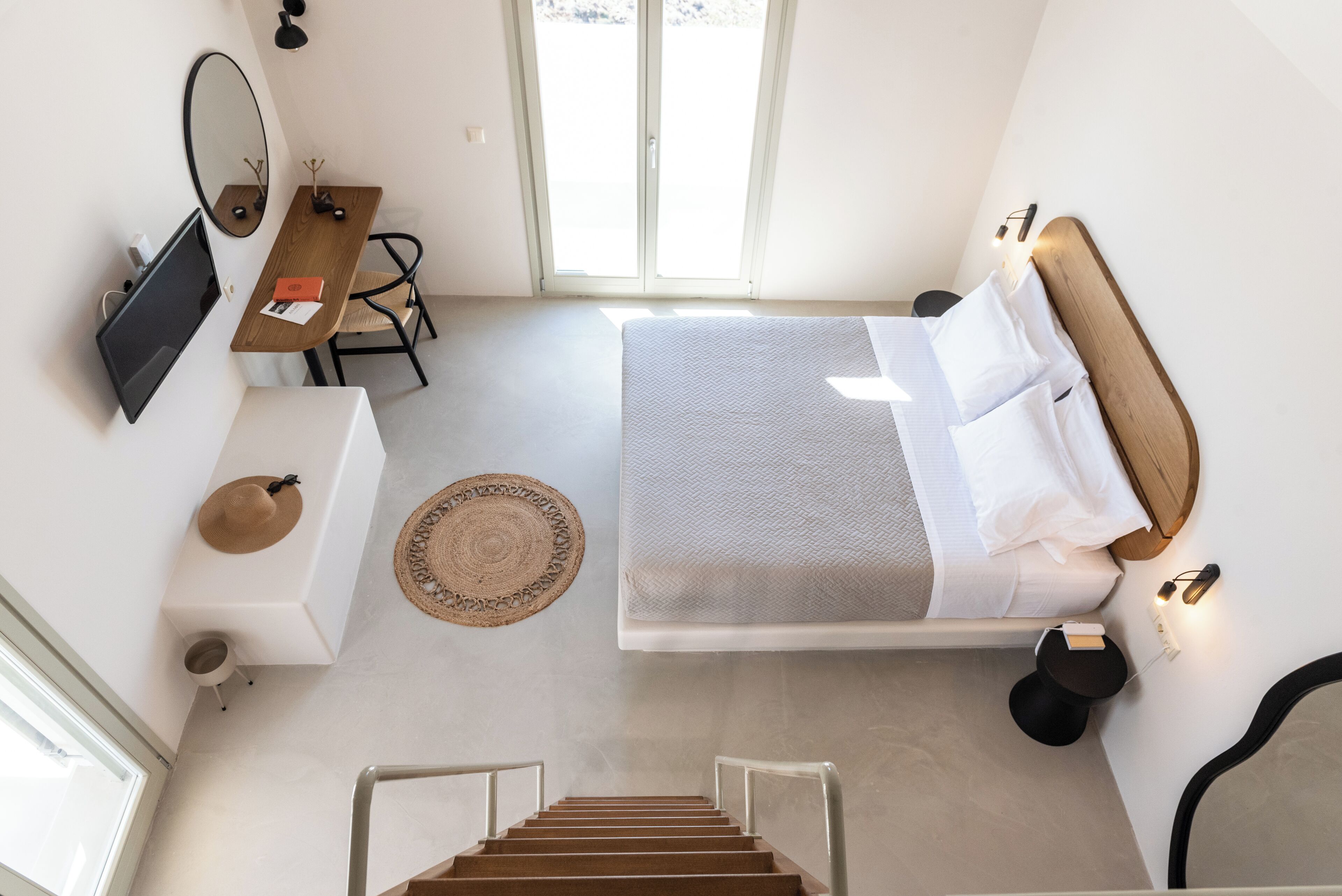 A bedroom with a bed, bedside table, and a desk with a chair.