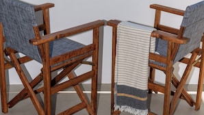 Een houten stoel en tafel voor een kustlandschap, met uitzicht op de zee en verre eilanden.