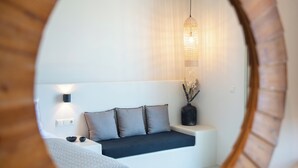 Een moderne slaapkamer met een wit bed, grijze kussens, een nachtkastje met een lamp en een hanglamp.