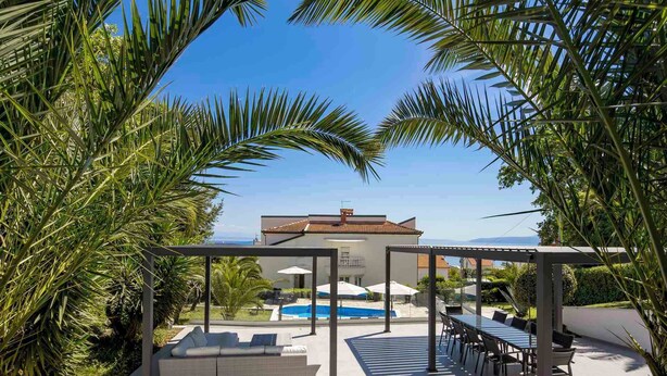 Une villa moderne dotée d’une piscine, d’un espace extérieur aménagé et offrant une vue sur la mer.