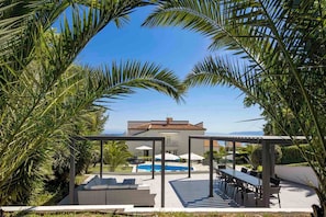 Una villa moderna con piscina, mobiliario exterior y vistas al mar.