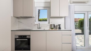 Une cuisine moderne dotée d’un four encastré, d’une fenêtre donnant sur un espace verdoyant et d’un grand appareil de climatisation.