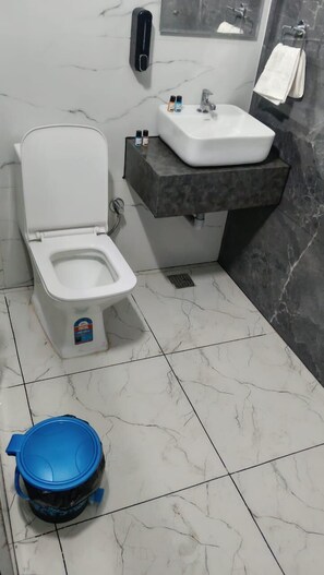 A bathroom with a toilet, sink, and marble-tiled floor. - The Golden Taj Vrindavan (Vrindavan)